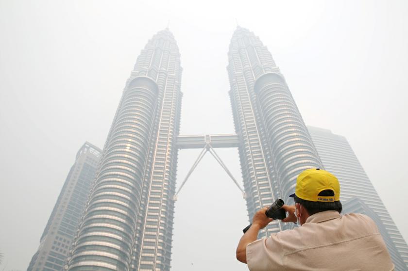 A tourist taking pictures of KLCC in the haze and it's surrounding from the foot of KLCC. u00e2u20acu201c Picture by Choo Choy May