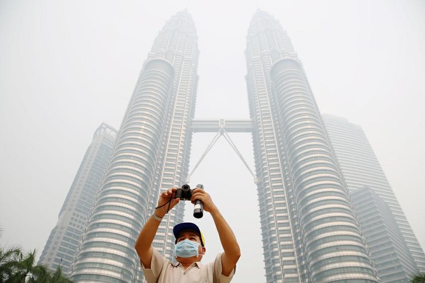 A tourist taking pictures of KLCC in the haze and it's surrounding from the foot of KLCC. u00e2u20acu201c Picture by Choo Choy May