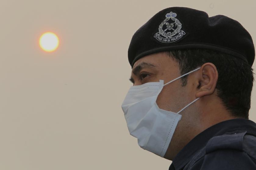  A police man wearing a mask with the sun behind him. u00e2u20acu201c Picture by Choo Choy May