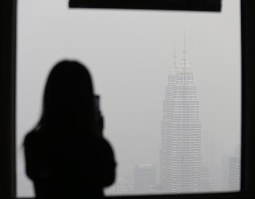 A tourist takes a picture of a haze-covered landmark of Malaysia, the Petronas Twin Towers, in Kuala Lumpur June 25, 2013. u00e2u20acu201d Reuters pic