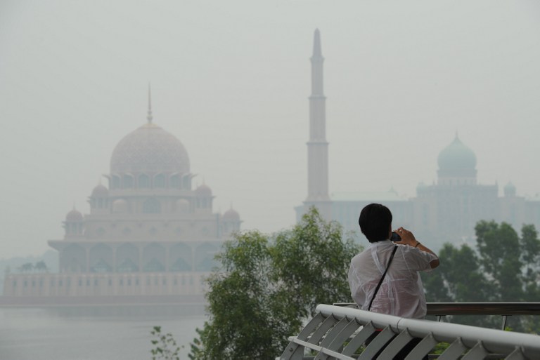 A visitor takes pictures as haze shrouds the Putra Mosque (left) and the Malaysian Prime Ministeru00e2u20acu2122s office in Putrajaya, outside Kuala Lumpur on June 26, 2013. u00e2u20acu201d AFP pic