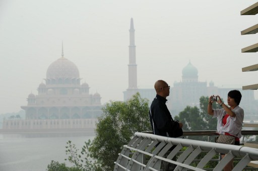 A visitor takes pictures as haze shrouds the Putra Mosque (left) and the Malaysian Prime Ministeru00e2u20acu2122s office in Putrajaya, outside Kuala Lumpur on June 26, 2013. u00e2u20acu201d AFP pic