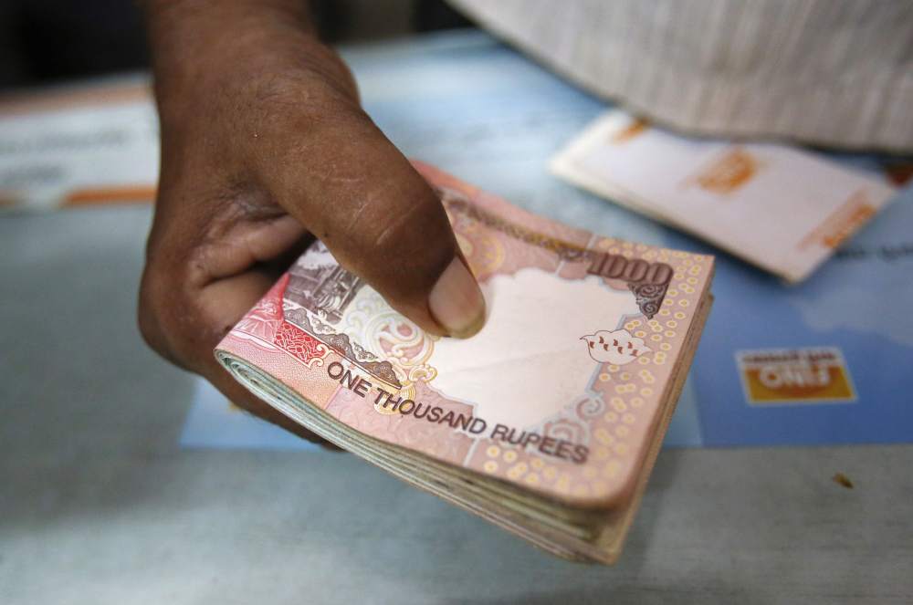 A customer hands a bundle of rupee notes to a teller at a financial institution in Mumbai on July 2, 2013. u00e2u20acu201d Reuters pic
