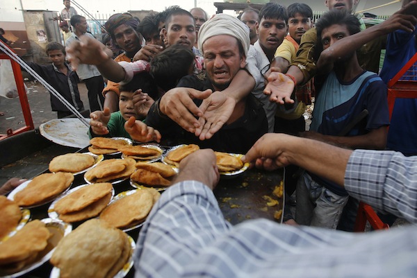 People reach out their hands as they wait to receive food provided by a charitable organisation outside a temple in New Delhi September 3, 2013. u00e2u20acu201d Reuters pic
