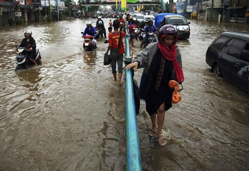 A woman holds a street divider as she walks through a flooded street in Jakarta, January 24, 2014. u00e2u20acu201d Reuters pic