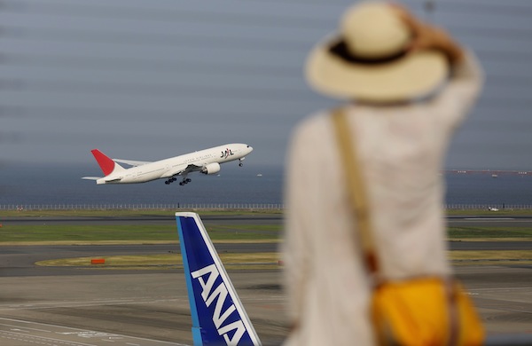 A woman watches a Japan Airlines (JAL) aeroplane taking off behind an All Nippon Airwaysu00e2u20acu2122 (ANA) aeroplane at Haneda airport in Tokyo August 8, 2013. u00e2u20acu201d Reuters pic