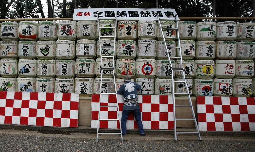 A man at Yasukuni Shrine in Tokyo December 26, 2013, placing barrels of dedicatory Japanese sake in place for celebrating upcoming New Year's day Reuters