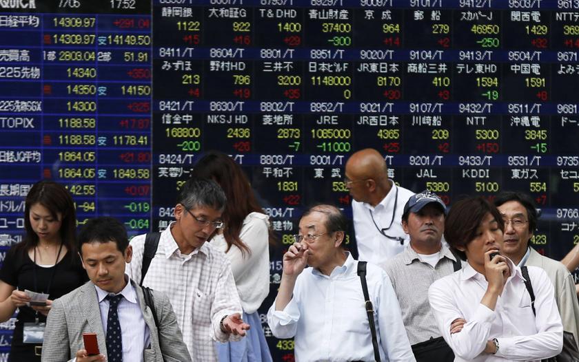 Passersby walk past an electric stock quotation board outside a brokerage in Tokyo July 5, 2013. u00e2u20acu201d Reuters pic