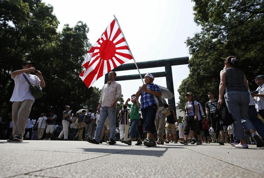 A family holds Japan's rising sun flag as they visit Yasukuni Shrine in Tokyo, on the anniversary of Japan's surrender in World War Two, August 15, 2013