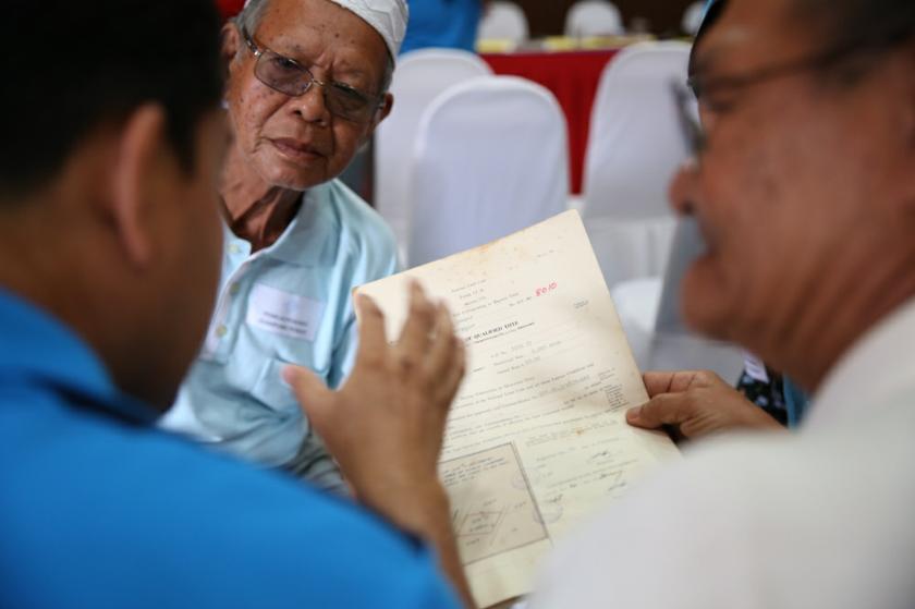 A man listens as a PKB officer conducts a consultation with a Kampung Baru landowner.