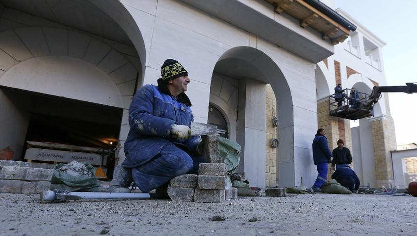 Construction workers work at the pavement at an unfinished apartment building in the mountain media village near Sochi, February 6, 2014, day before opening Reuters