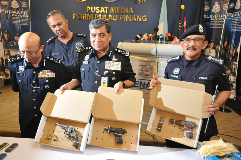 Inspector General of Police Tan Sri Khalid Abu Bakar (centre) showing the pistols recovered from the scene of the pre-dawn shoot out that killed five men. With him is Penang police chief Datuk Abdul Rahim Hanafi (right).  u00e2u20acu201d Picture by K. E. Ooi