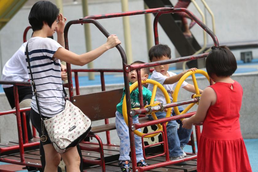 A mother watches her two boys play on a swing at a playground at the KLCC park in Kuala Lumpur.u00e2u20acu201d Picture by Choo Choy May