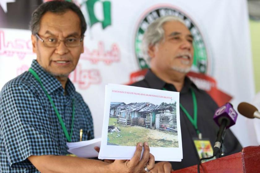 Dr Dzulkefly Ahmad with a photograph of dilapidated houses in Kampung Pachakan, Kuala Besut. On the right is PAS secretary-general Datuk Mustafa Ali. u00e2u20acu201d Picture by Saw Siow Feng