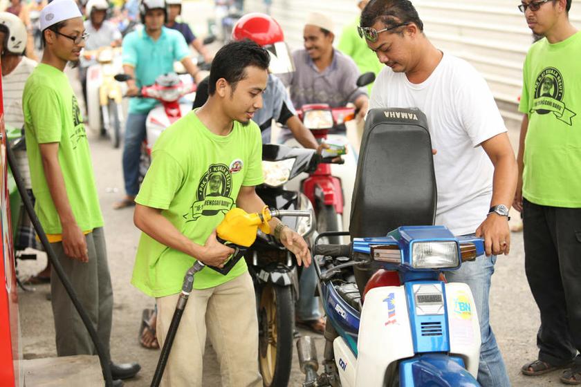 A PAS Youth member fills up with free petrol the motorcycle of a rider in Kuala Besut on July 23, 2013 as other riders wait in the queue. u00e2u20acu201d Picture by Saw Siow Feng