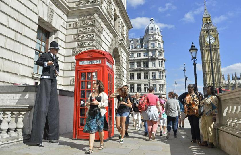 Tourists walk past entertainer Tommy West, dressed as u00e2u20acu02dcPC Long Tomu00e2u20acu2122, in Parliament Square in central London on August 30, 2013. u00e2u20acu201d Reuters pic