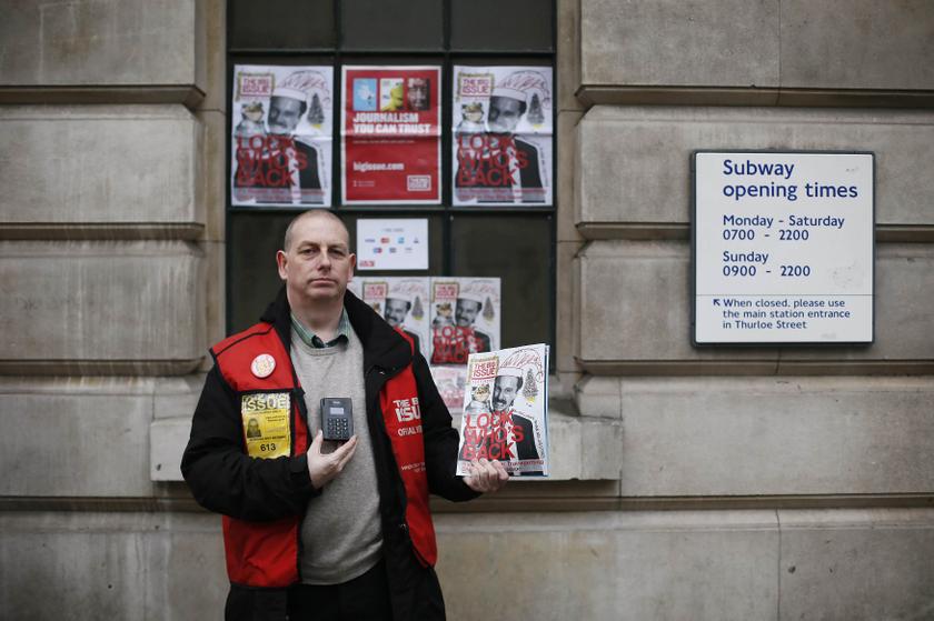Big Issue vendor Simon Mott poses for a photograph with a copy of the magazine and a Chip and Pin device outside South Kensington Tube Station in London November 28, 2013. u00e2u20acu201d Reuters pic