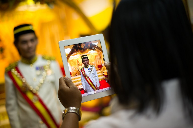 This picture taken on September 7, 2013 shows a man taking pictures of a u00e2u20acu02dcDatuku00e2u20acu2122 given by a self-styled royal Raja Noor Jan Shah Raja Tuah Shah before attending a private event at a palace in Gombak. u00e2u20acu201d AFP pic