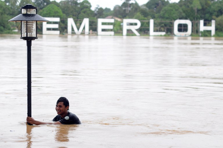  A youth holds on to a lamp post while playing in floodwaters in Temerloh, Pahang, December 5, 2013. u00e2u20acu201du00c2u00a0AFP pic