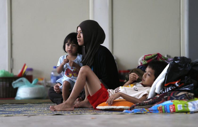 An evacuee sits with her children inside a relief centre at Kemaman, 300km outside Kuala Lumpur December 6, 2013. u00e2u20acu201d Reuters pic