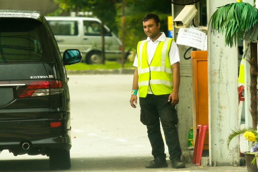 A guard at a housing area in Puchong checks a car. There are 30,000 illegal security guards in the country who work at condominiums, business premises and even banks.