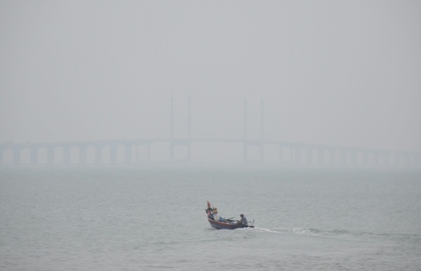 A fisherman returns from his daily catch and passes a barely visible Penang Bridge at 2pm, as the API reached 100 in Seberang Jaya and 97 for Penang island on July 28, 2013. u00e2u20acu201d Picture by K.E. Ooi