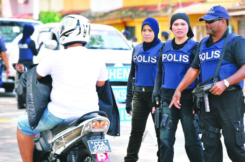 Police officers checking a motorcyclist passing by SMK Sri Rampai. — Picture by The Malay Mail