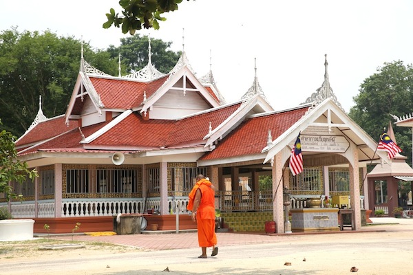 A young Buddhist monk walks in front of the meditation hall in Wat Pikulthong.