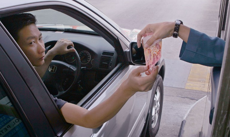 A Malaysian highway user pays a toll station in Kuala Lumpur, 29 December 2006. u00e2u20acu201d AFP pic