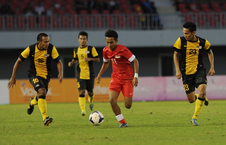 Muhammad Fariz Ramli (Red) of Singapore fights for the ball against Malaysia's team players during their football match at the 27th Southeast Asian SEA Games at Zeyar Thiri stadium in Naypyidaw on December 15, 2013. u00e2u20acu201d AFP pic