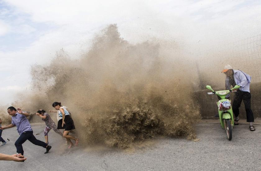 Visitors run away as waves from a tidal bore surge past a barrier on the banks of Qiantang River, in Hangzhou, Zhejiang province. u00e2u20acu201c Reuters pic