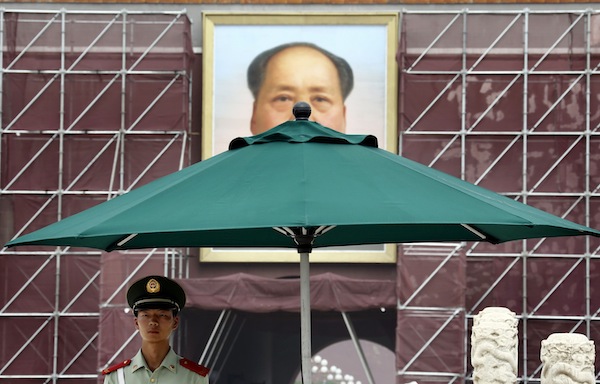 A paramilitary police official stands guard in front of a giant portrait of Chinau00e2u20acu2122s late leader Mao Zedong, which is surrounded by scaffolding during a decoration work, at the Tiananmen Gate in Beijing August 28, 2013. u00e2u20acu201d Reuters pic