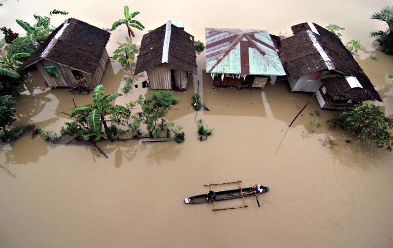 Residents paddle past submerged houses after flooding brought about by heavy rains in the outskirts of Butuan City, Agusan del norte province, on the island of Mindanao on January 13, 2014. — AFP pic