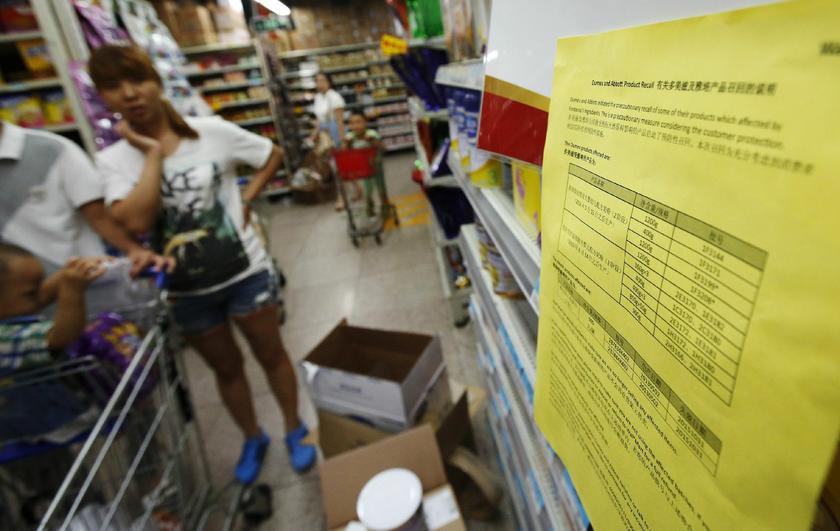 A woman at a supermarket in Beijing, August 7, 2013, looks at a notice about the product recall of some of Dumex and Abbott’s milk powder products. — Reuters pic