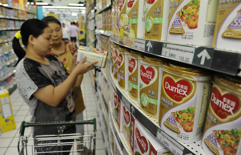 A sales assistant (rear) at a supermarket in Hefei, Anhui province, August 5, 2013, helps a customer to select Dumex milk powder. — Reuters pic
