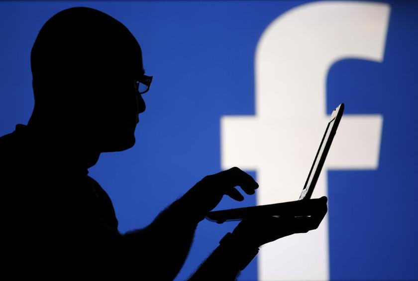A man is silhouetted against a video screen with an Facebook logo as he poses with a Dell laptop in this photo illustration taken in the central Bosnian town of Zenica, August 14, 2013 Reuters