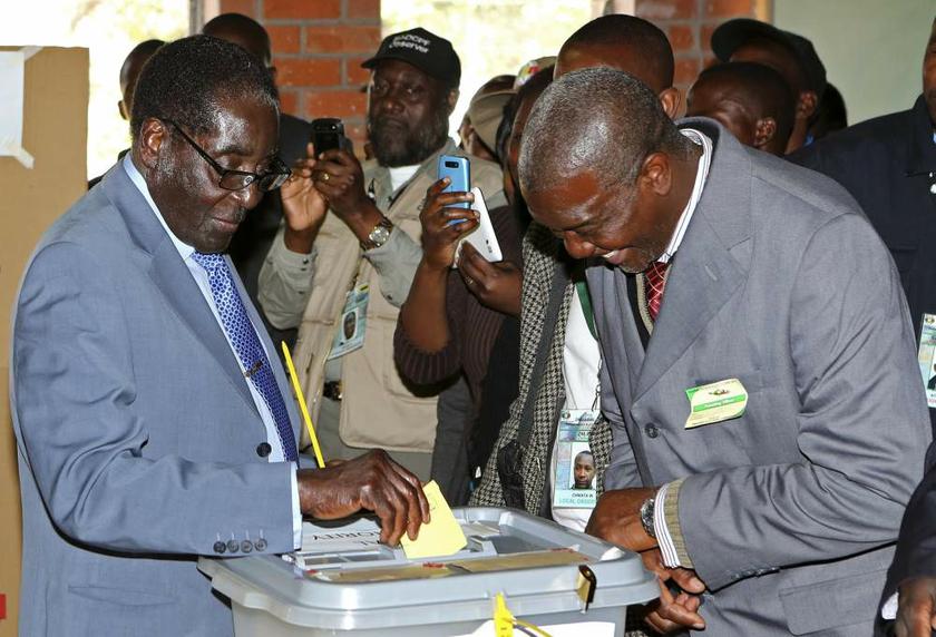 Zimbabwe President Robert Mugabe (left) casts his vote as an election officer looks on in Highfields outside Harare on July 31, 2013. u00e2u20acu201d Reuters pic