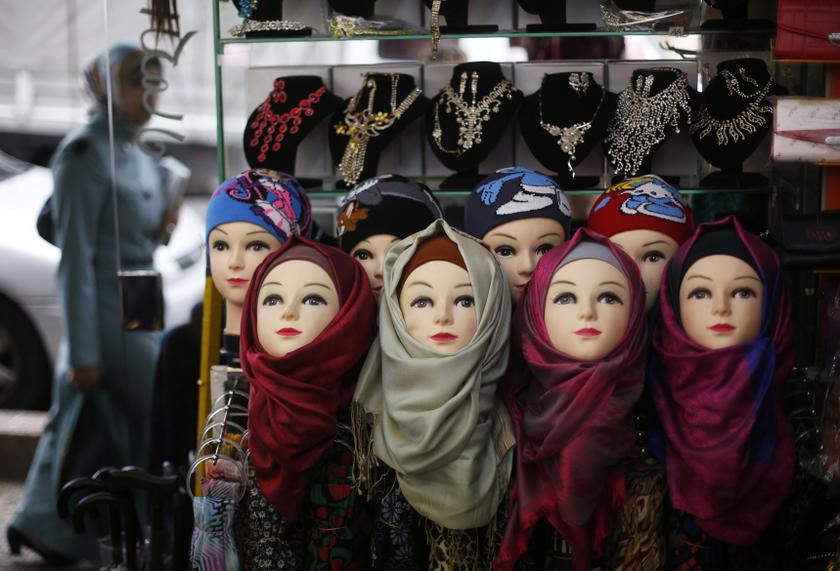 A Palestinian woman walks past a shop selling head scarves in the West Bank city of Ramallah December 4, 2013. u00e2u20acu201d Reuters pic