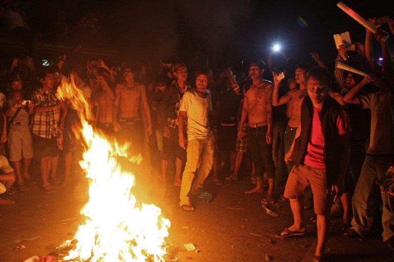 This picture taken late on December 16, 2013 shows Myanmar soccer fans setting fire to clothes on a road near the Thuwunna stadium in Yangon after Indonesia defeated Myanmar in their 27th SEA Games quarter-final match. u00e2u20acu201d AFP pic