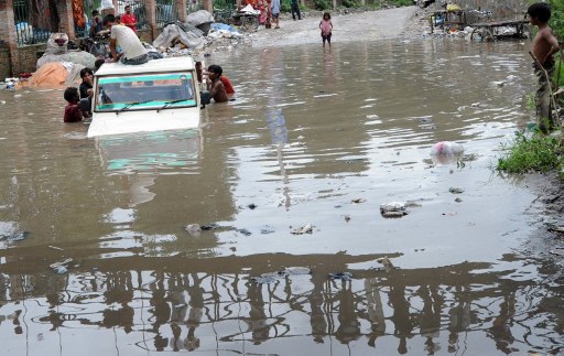 A reflection of bystanders on a bridge is seen as they watch a Nepalese driver and a passenger are helped push their jeep out of flood water on a road near Bagmati River in Kathmandu on July 20, 2011. u00e2u20acu201d AFP pic