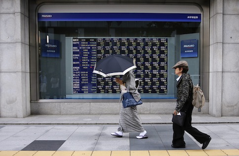A woman wearing a kimono holds an umbrella as she walks past an electronic stock quotation board outside a brokerage in Tokyo May 23, 2013. u00e2u20acu201d Reuters pic