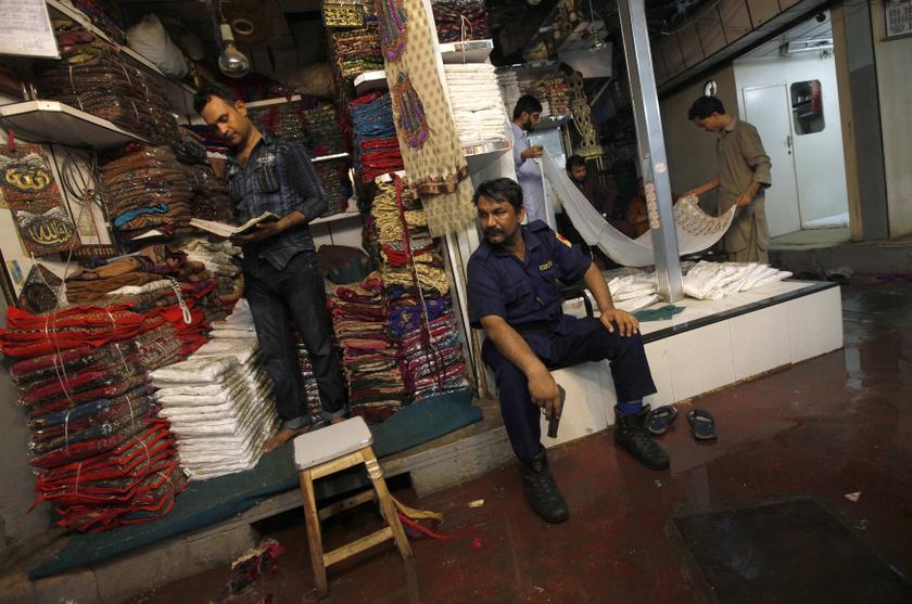 A private armed security guard keeps his eyes on a passage as shopkeepers work along a covered cloth market in Karachi June 13, 2013. u00e2u20acu201d Reuters pic