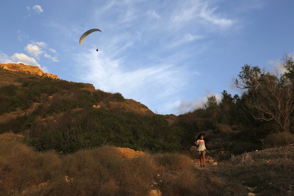 A young girl walks along a path as a paraglider soars overhead at Ghajn Tuffieha (Appleu00e2u20acu2122s Eye) Bay on the northwest coast of Malta September 19, 2013. u00e2u20acu201d Reuters pic