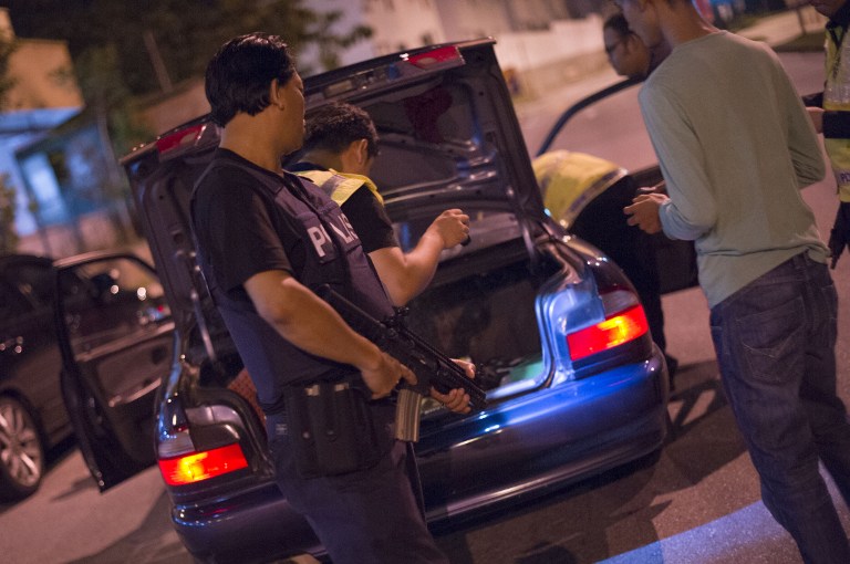 This picture taken in the early hours of August 21, 2013 shows Malaysian policemen checking a vehicle at a roadblock during an operation called 'Op Cantas Khas' in Kuala Lumpur. u00e2u20acu201c AFP pic