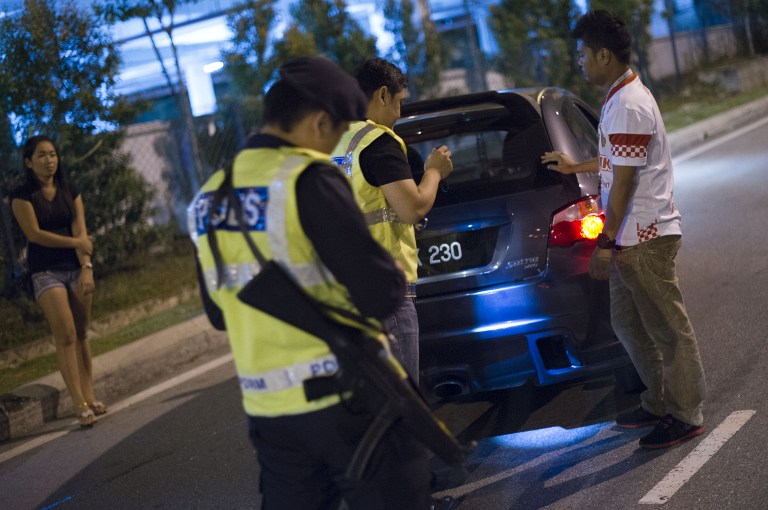 This picture taken in the early hours of August 21, 2013 shows Malaysian policemen checking a vehicle at a roadblock during an operation called 'Op Cantas Khas' in Kuala Lumpur. u00e2u20acu201c AFP pic
