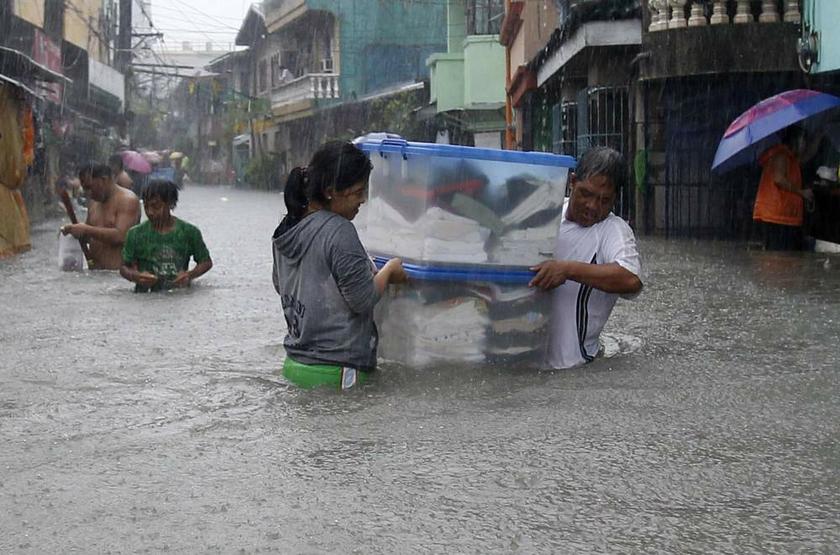 Residents carry their belongings as they wade through floodwaters brought by the monsoon rain, intensified by tropical storm Trami, in Paranaque city, metro Manila on August 20, 2013. u00e2u20acu201d Reuters pic