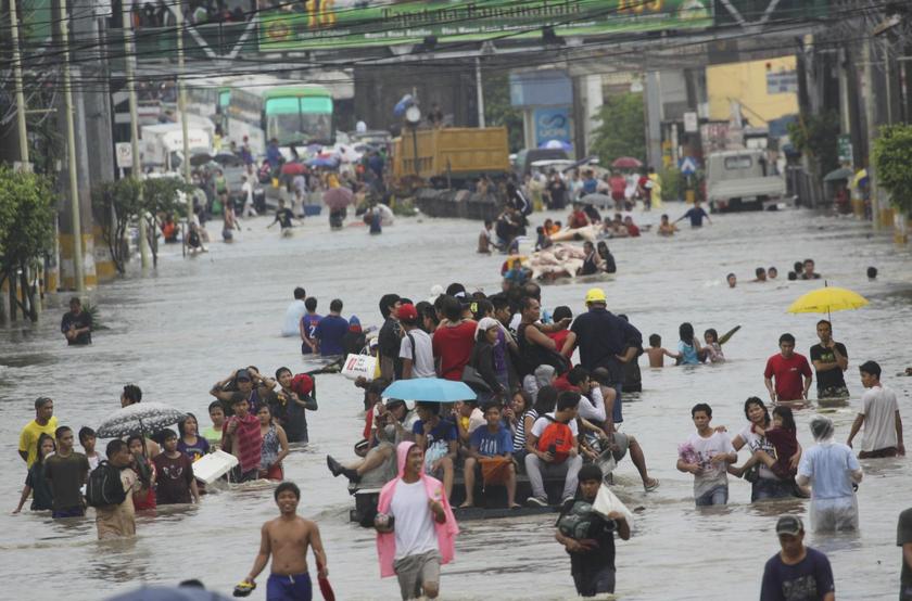 People wade through floodwaters brought by monsoon rain and intensified by tropical storm Trami, in Las Pinas city, south of Manila August 19, 2013