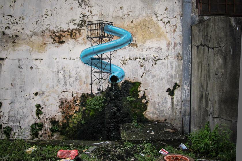 A mural depicts a water slide that connects to plastic drainage pipe in a wall, in Johor Baru. — Picture from Zacharevic’s Facebook page.