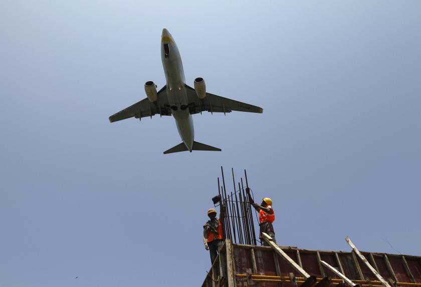 Construction workers erect scaffolding at the site of metro station as an aircraft flies past in the southern Indian city of Chennai in this August 29, 2013 file photo. u00e2u20acu201d Reuters pic