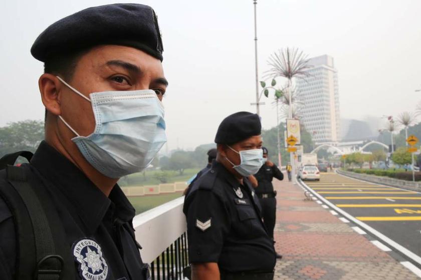 Policemen on duty at Parliament House on June 24, 2013 wear masks to protect themselves from the haze. u00e2u20acu201d Picture by Choo Choy May